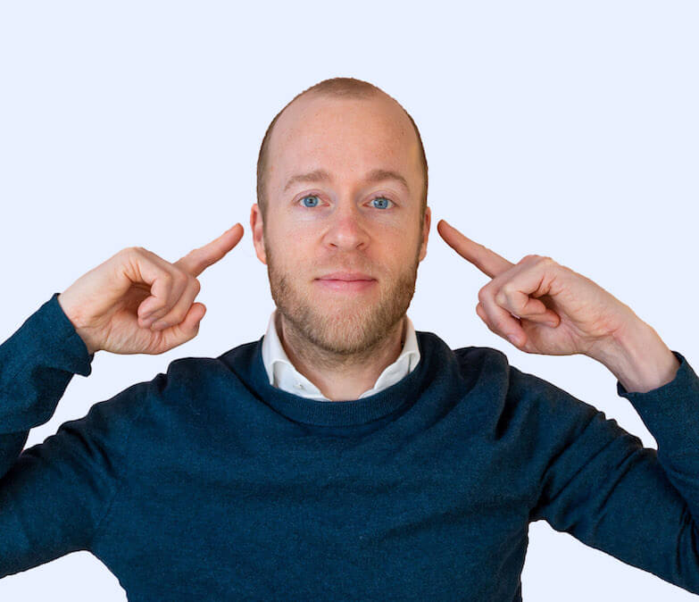 Roel van Gorkum, oprichter van Still Tinnitus, wijst naar zijn oren om te laten zien dat hij geen last meer van tinnitus heeft