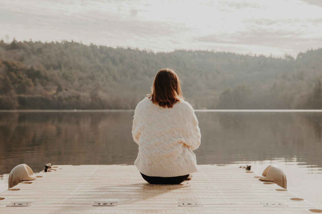 Woman sitting at the edge of a lake in the forest meditating