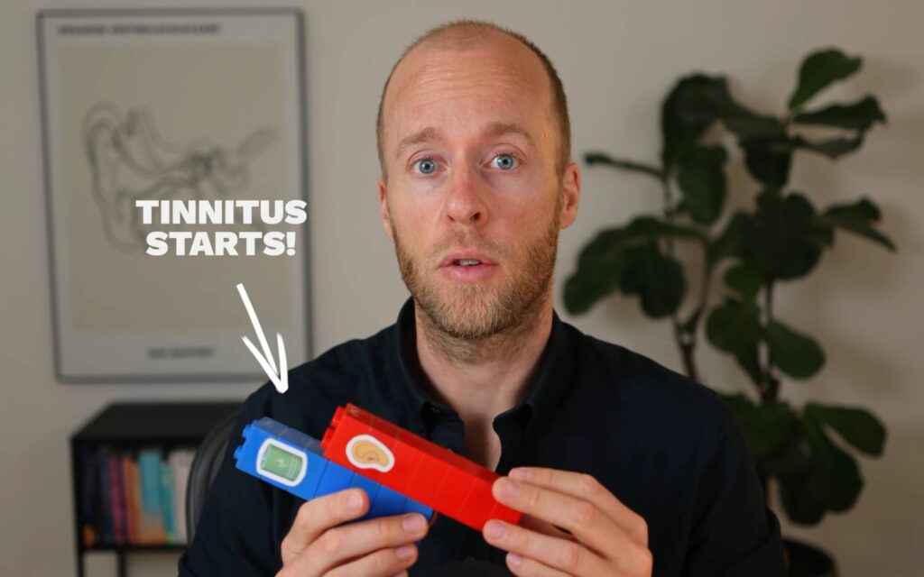 Roel van Gorkum, founder of Still Tinnitus, holding up 2 pillars made of lego to illustrate how hearing loss and stress are related