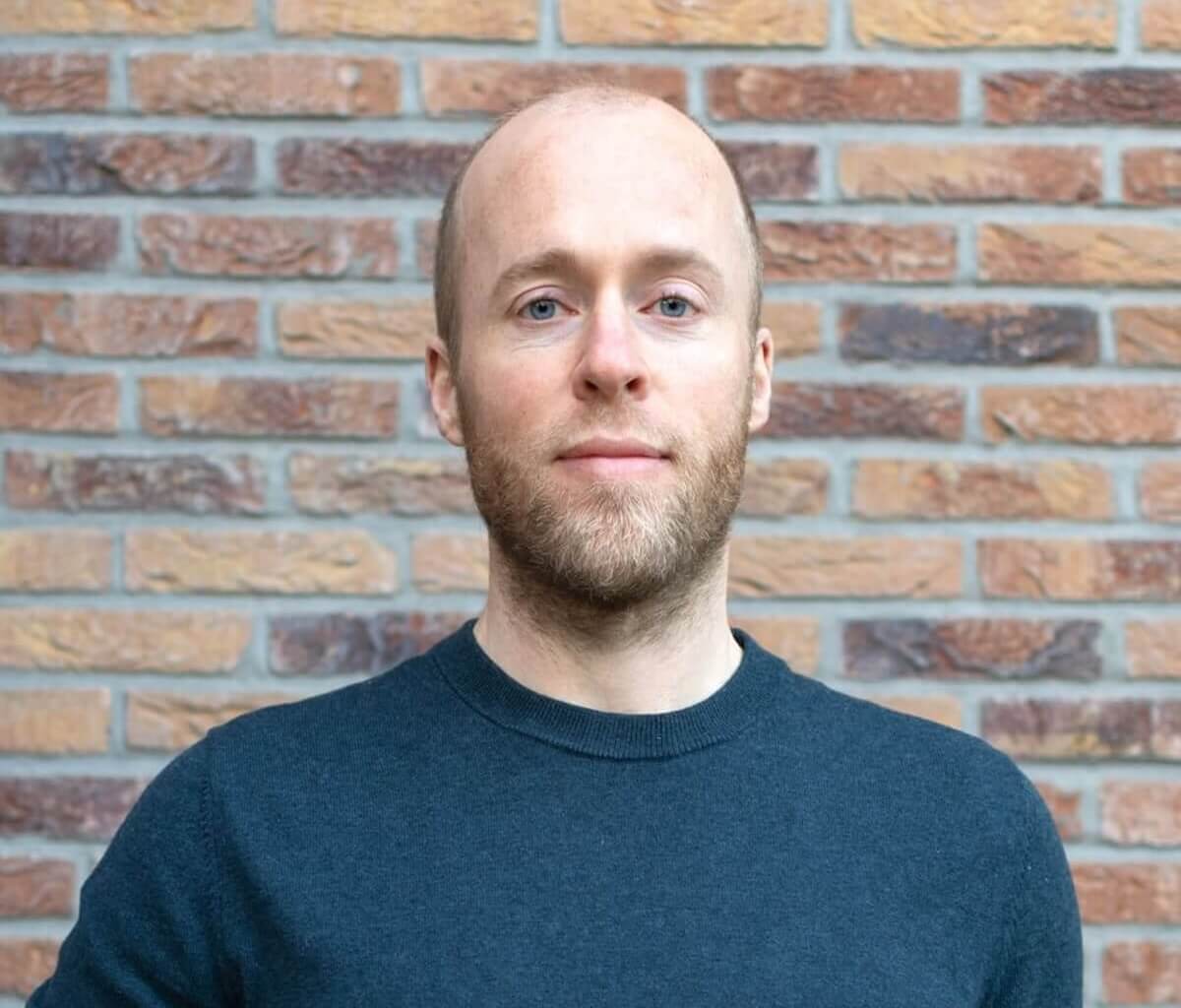 Roel van Gorkum, oprichter van Still Tinnitus, staat voor een stenen muur.