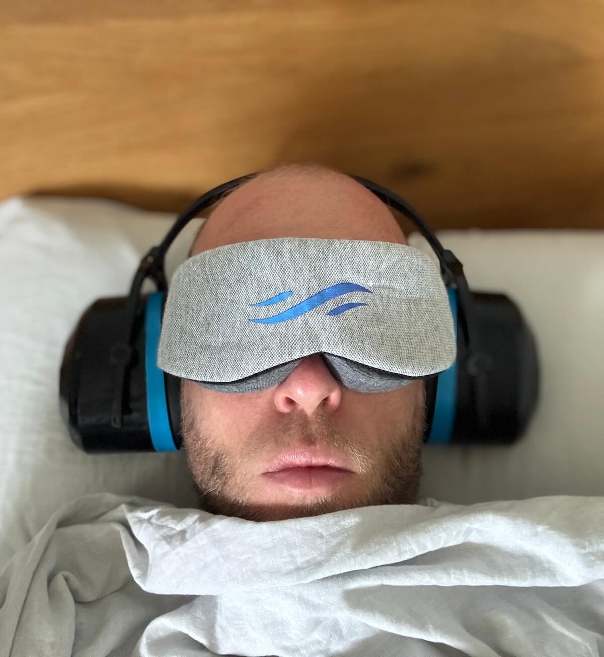 Roel van Gorkum die in bed ligt met een slaapmasker en een koptelefoon op.