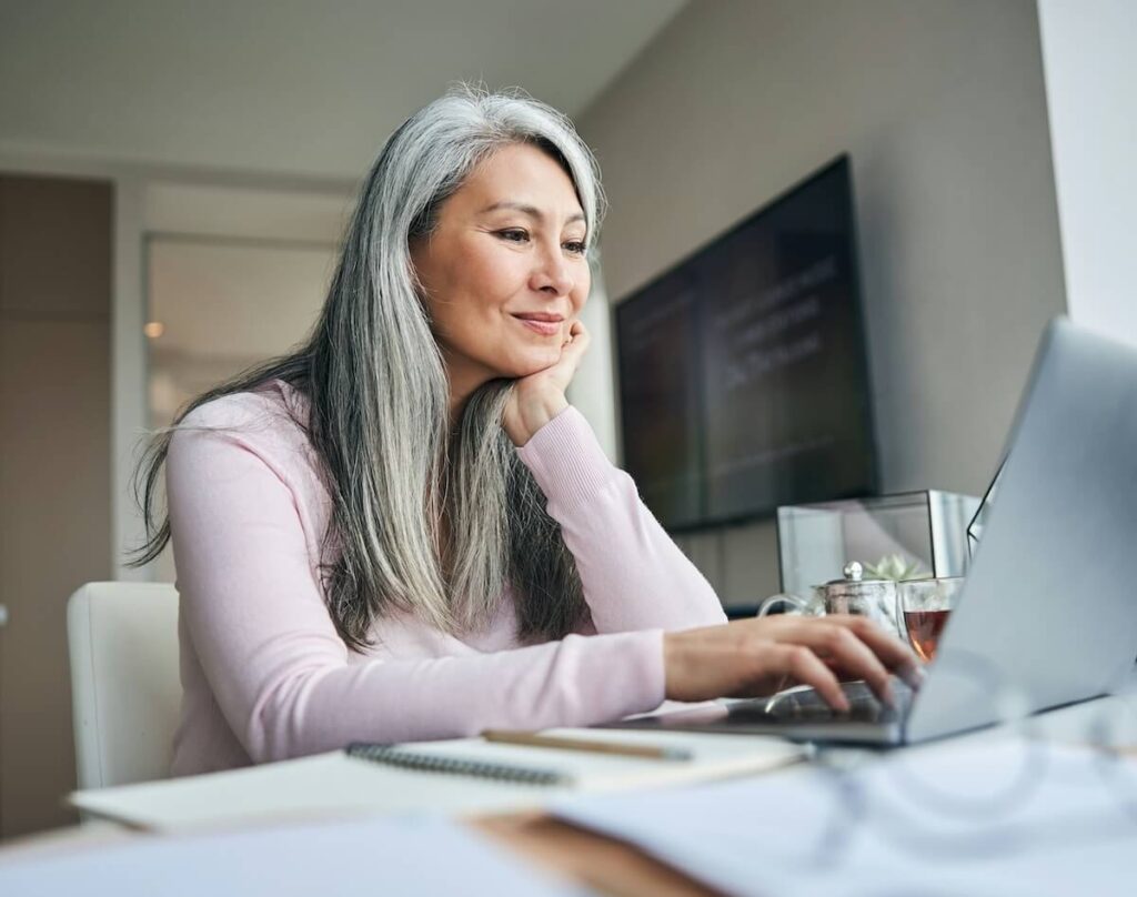 Vrouw die een laptop gebruikt om de Tinnitus Functional Index (TFI)-test in te vullen, ter illustratie van het beoordelen van hoe tinnitus het dagelijks leven beïnvloedt.