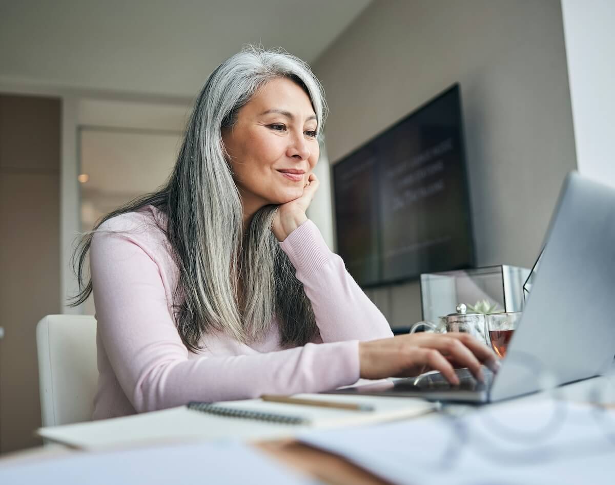 Vrouw die een laptop gebruikt om de Tinnitus Functional Index (TFI)-test in te vullen, ter illustratie van het beoordelen van hoe tinnitus het dagelijks leven beïnvloedt.